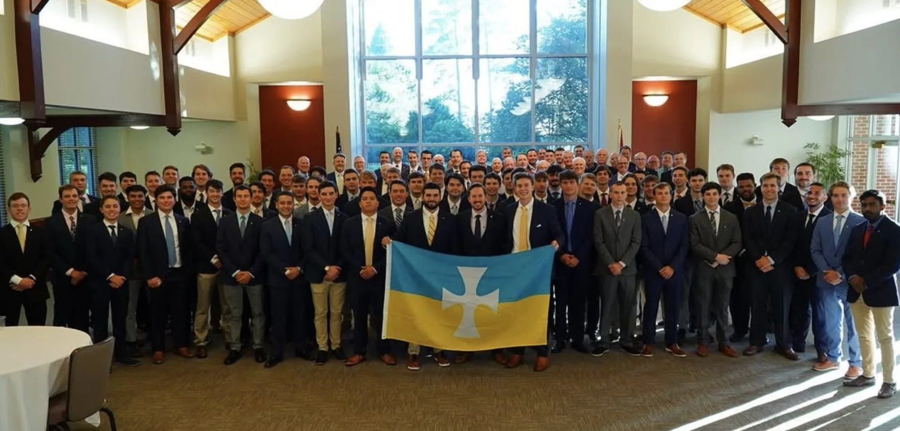 The active brothers of Epsilon Zeta holding the chapter flag at a 2026 formal gathering